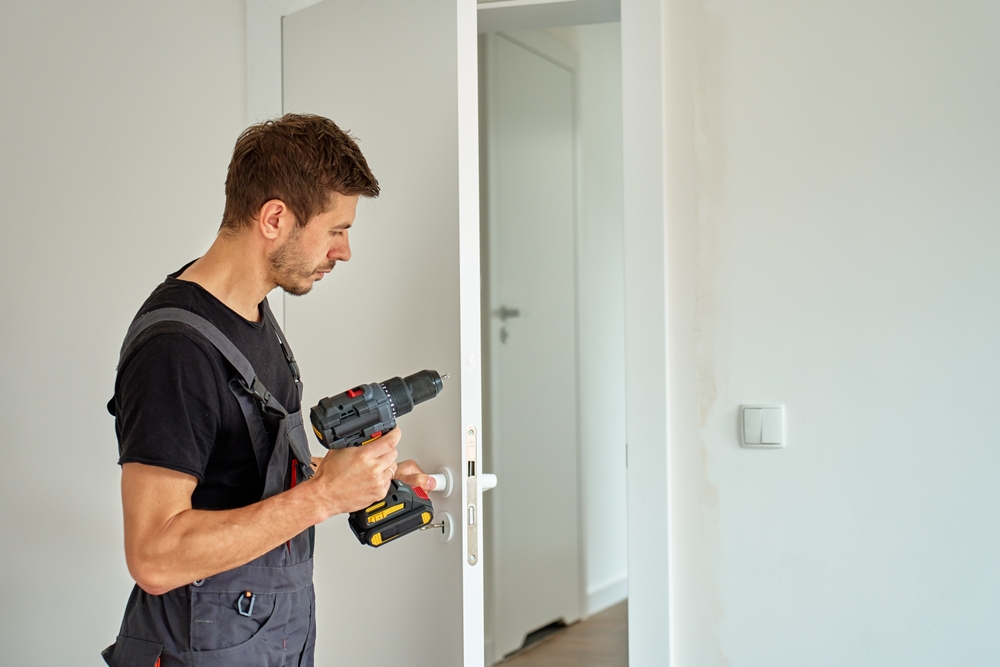 Technician adjusting interior door hinges and frame to fix a door not closing properly in a home
