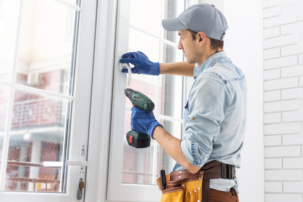 Technician repairing sliding glass doors hard to open because of worn rollers and track buildup