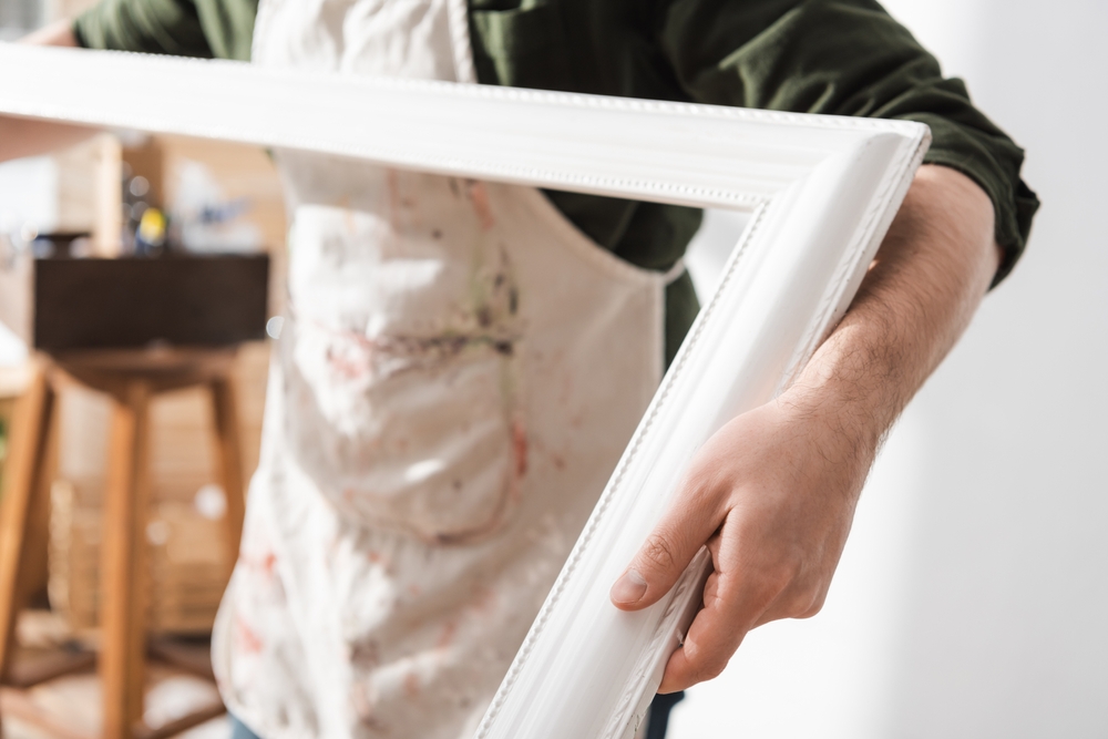 Homeowner inspecting hidden wall damage behind large mirrors on your wall after many years