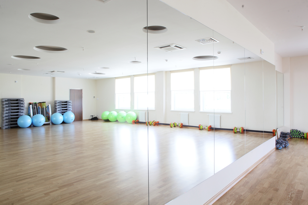Professional installer measuring and installing a custom gym wall mirror in a La Quinta home gym