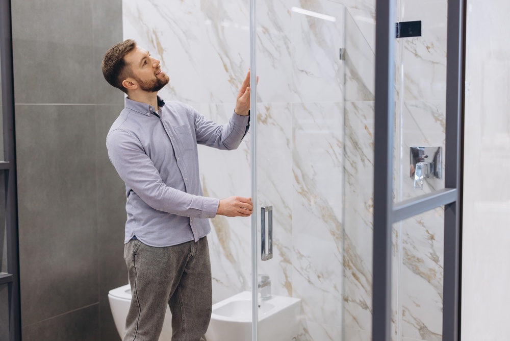 Professional technician inspecting a tempered glass shower door that unexpectedly shattered