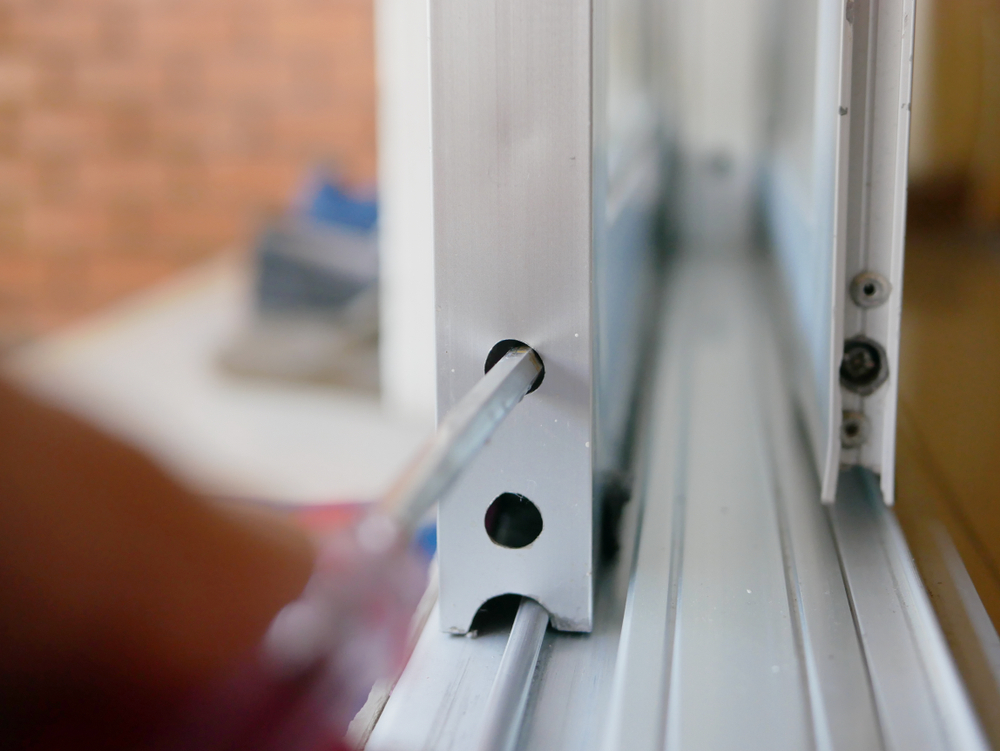 Technician inspecting sliding glass door rollers to determine whether repair or replacement is needed