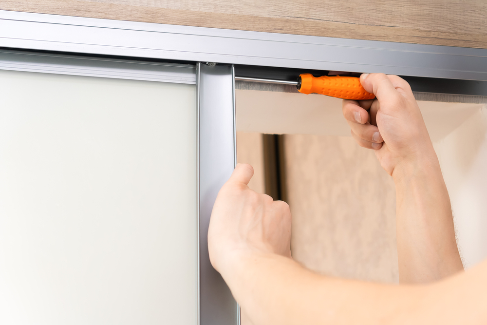 Technician repairing a sliding glass door that is hard to open