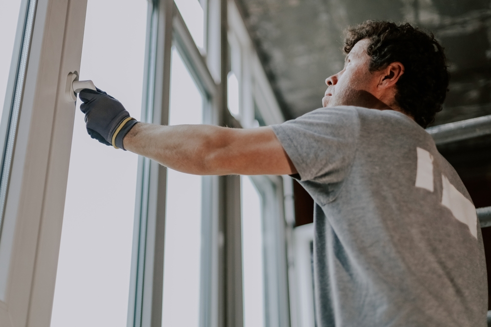 Homeowner inspecting windows for signs it's time to replace home windows